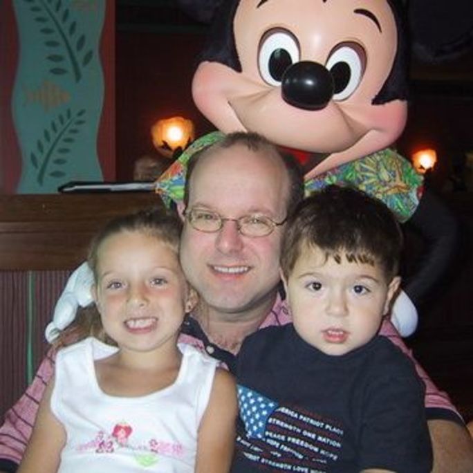 Photo of man proudly posing with his two young children.