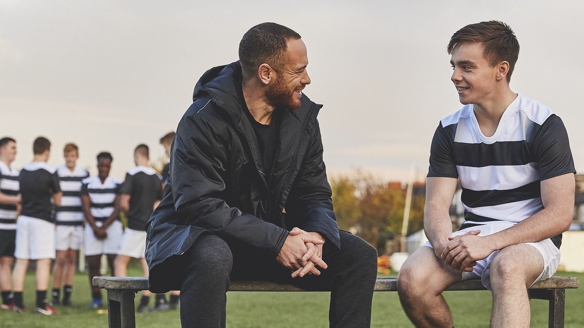 A coach and a player sitting together and smiling