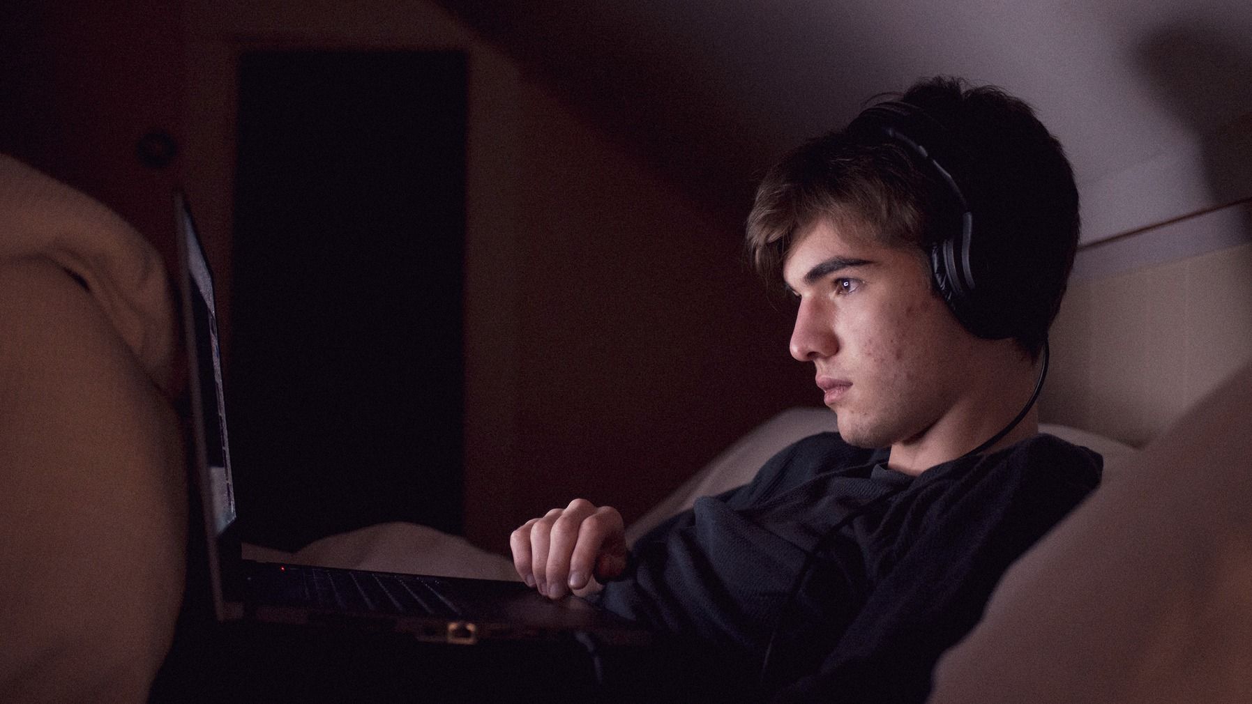 Boy sat in bed looking at laptop
