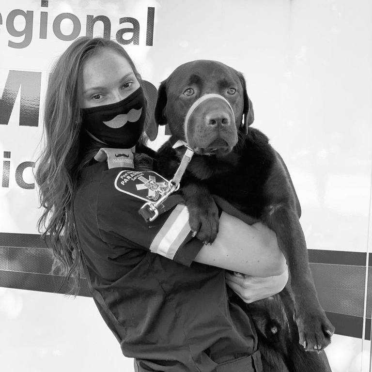 Peel Paramedics first responder in Movember-branded mask holding adorable dog for the camera