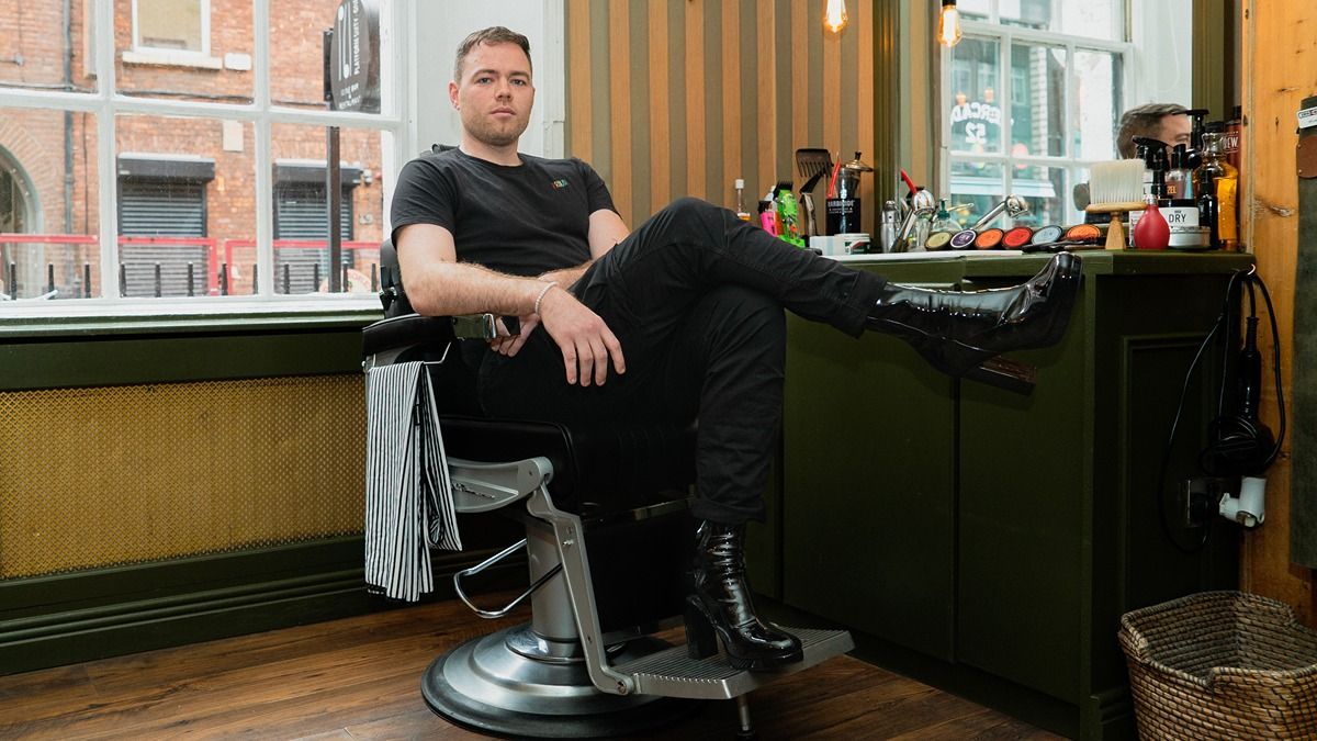 Cian sat in a barber chair wearing heels