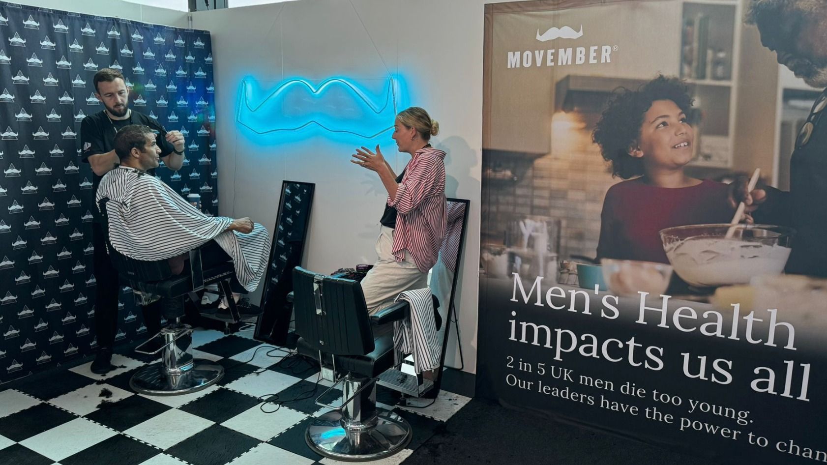 Movember advocacy team speaking to someone as he gets his hair cut