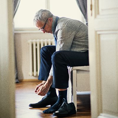 Photo of middle-aged man tying up his shoes.