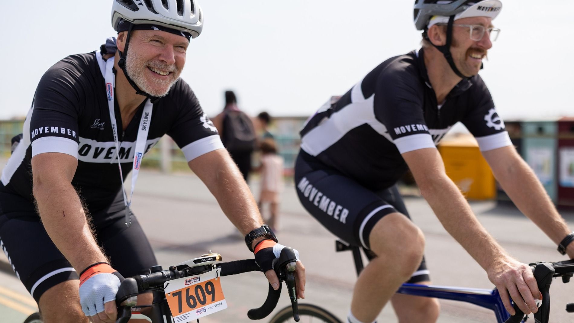 Photo of Movember supporter Stephen and a friend, cycling while wearing their Movember kit.