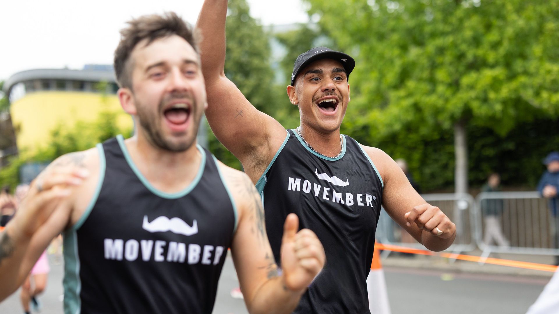 Smiling marathon runners in Movember-branded attire smiling to camera.