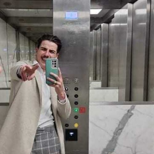 Superbly well-dressed young man taking selfie photo and giving V for victory hand sign.