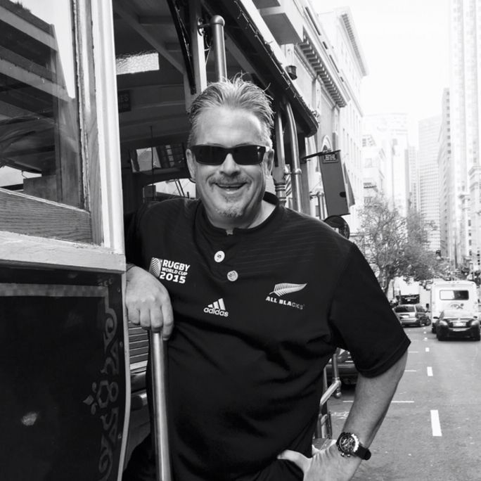 Photo of a man in sunglasses, smiling to camera.