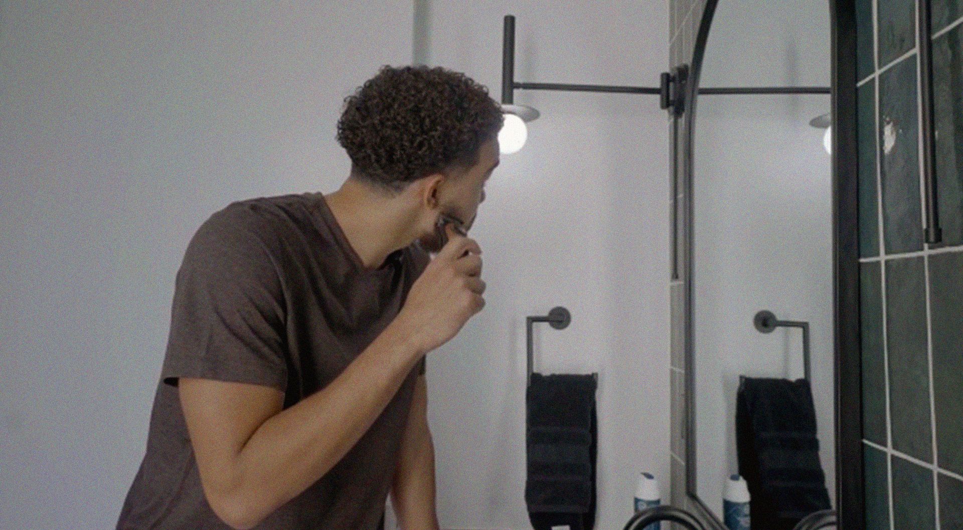 Photo of a man shaving in a bathroom.