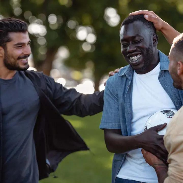 Three young men laughing and playing sport.