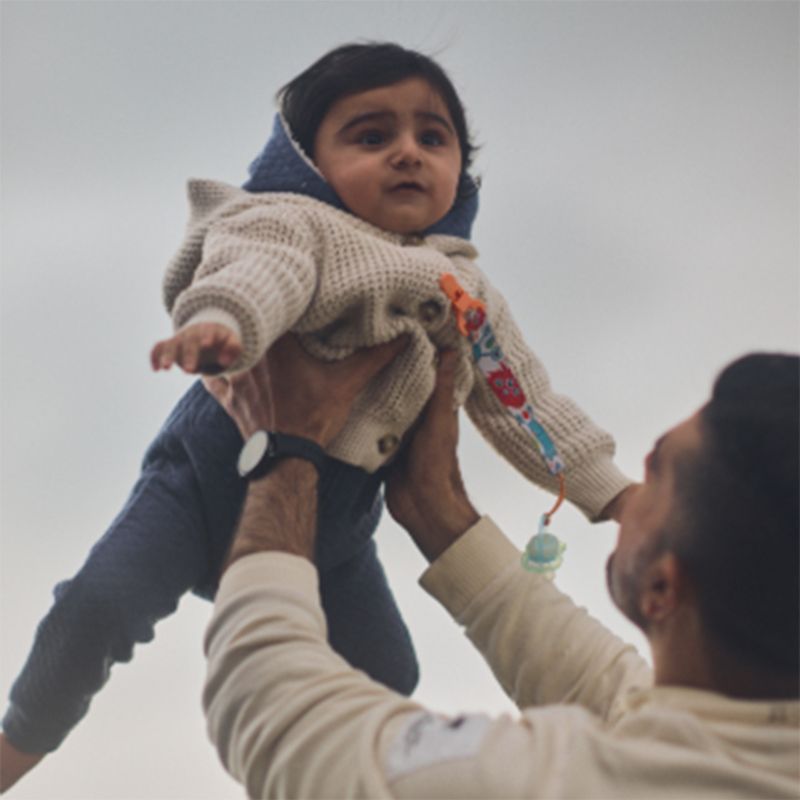 A father lovingly holding up an infant girl.