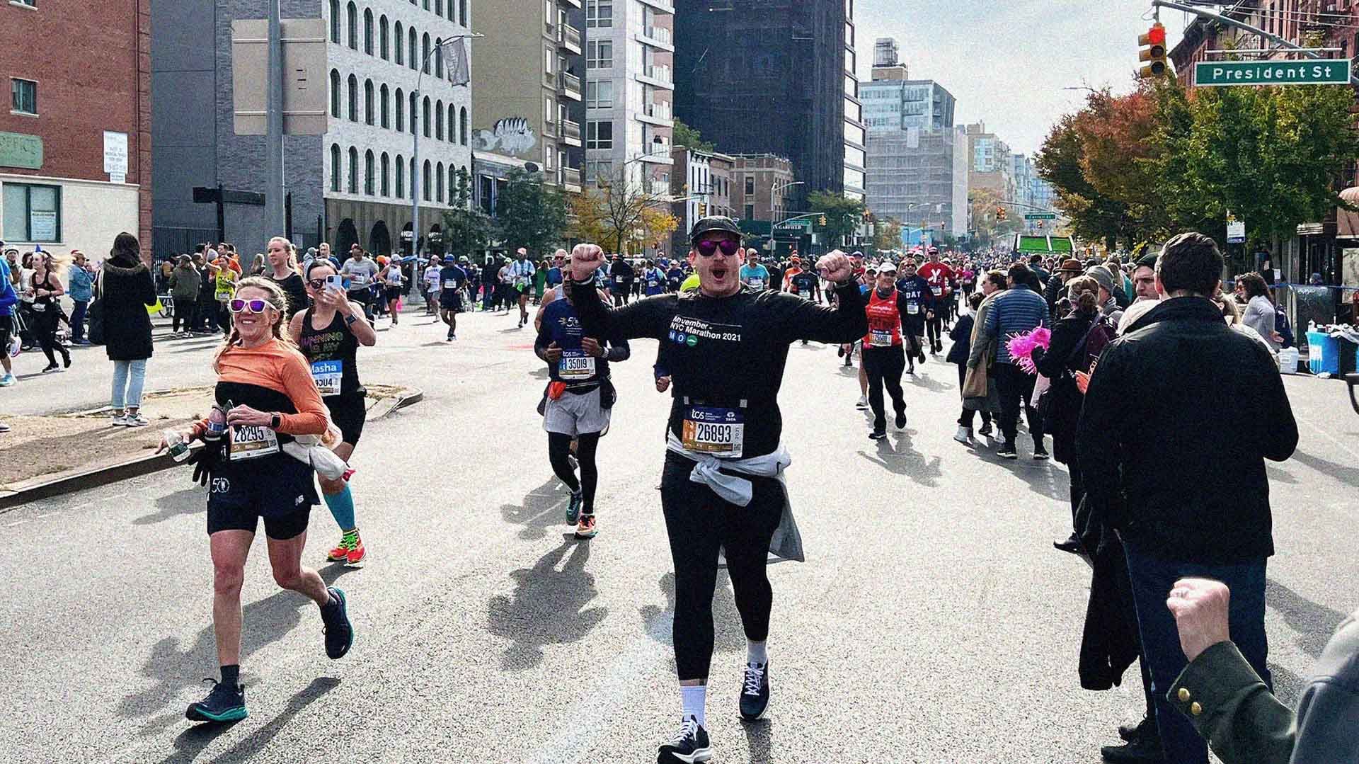 Runners competing in New York City Marathon, triumphantly running past camera.