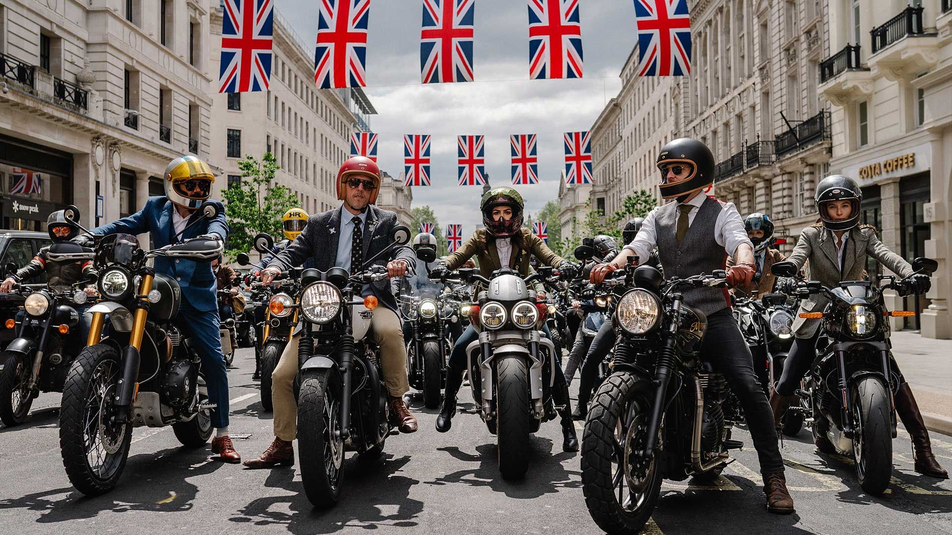 Dapper motorcyclists, assembled for a charity ride on a lively urban street. Union Jack banners are visible behind them.