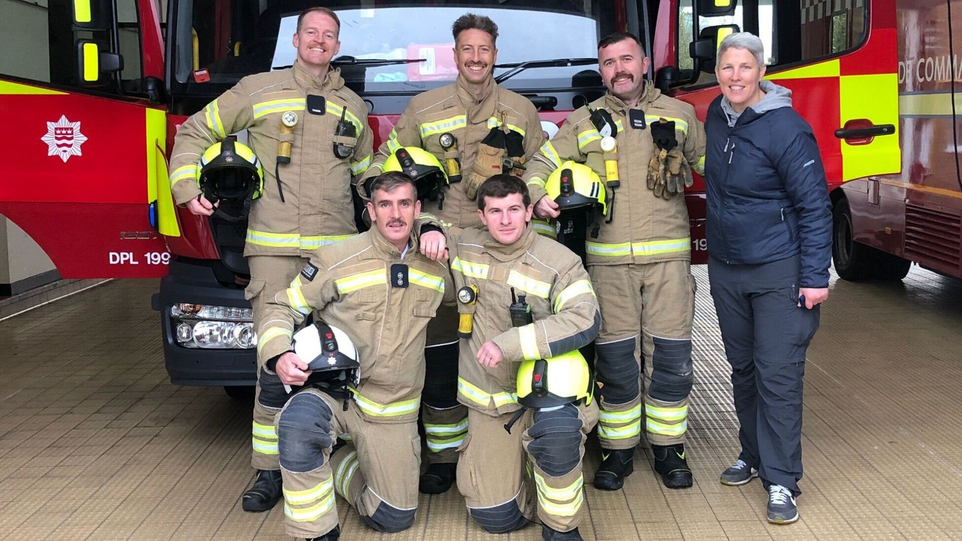 Fire brigades smiling in front of a fire engine