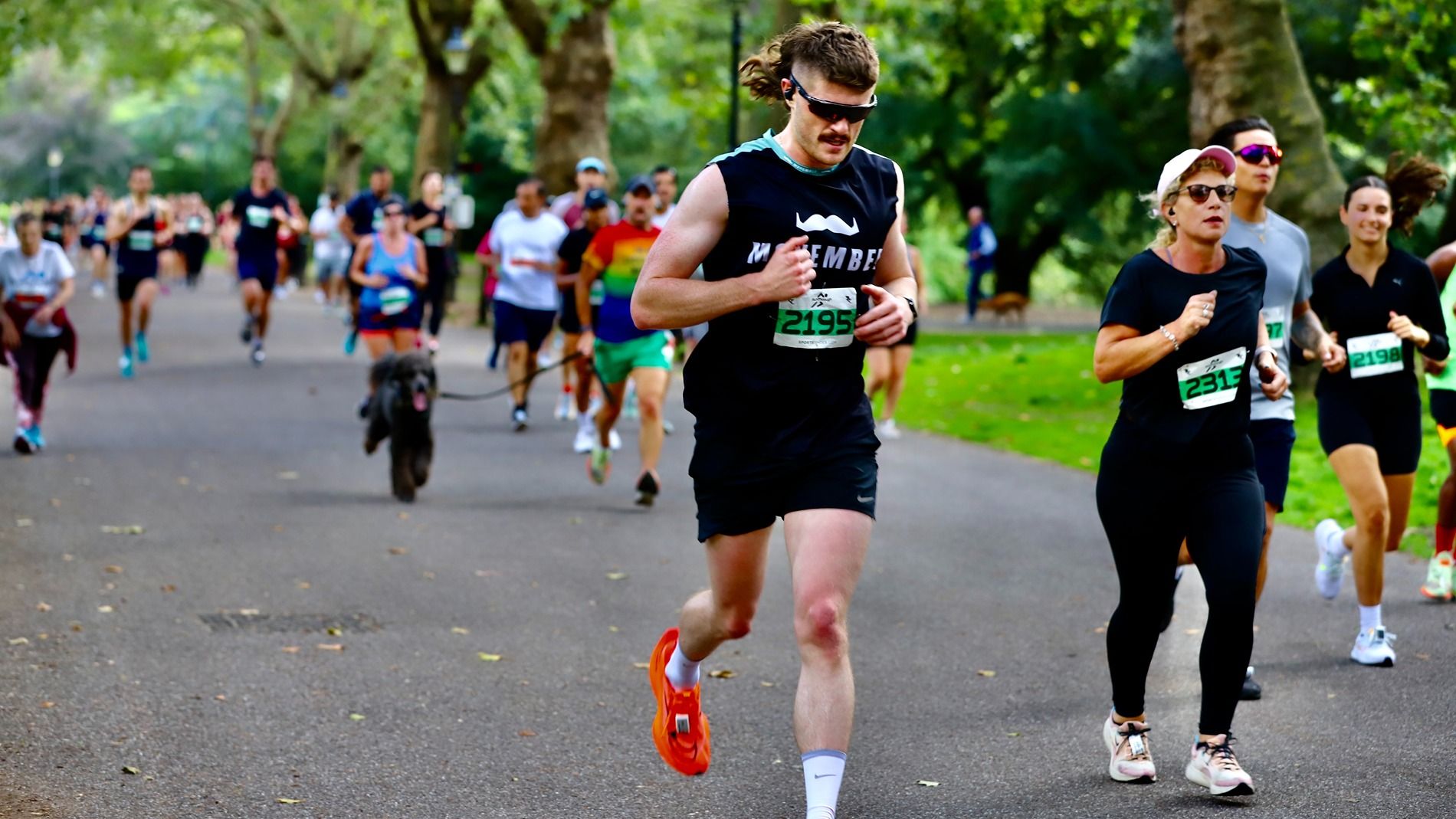 Photo of athletic man, running in a busy race, wearing Movember-branded attire.