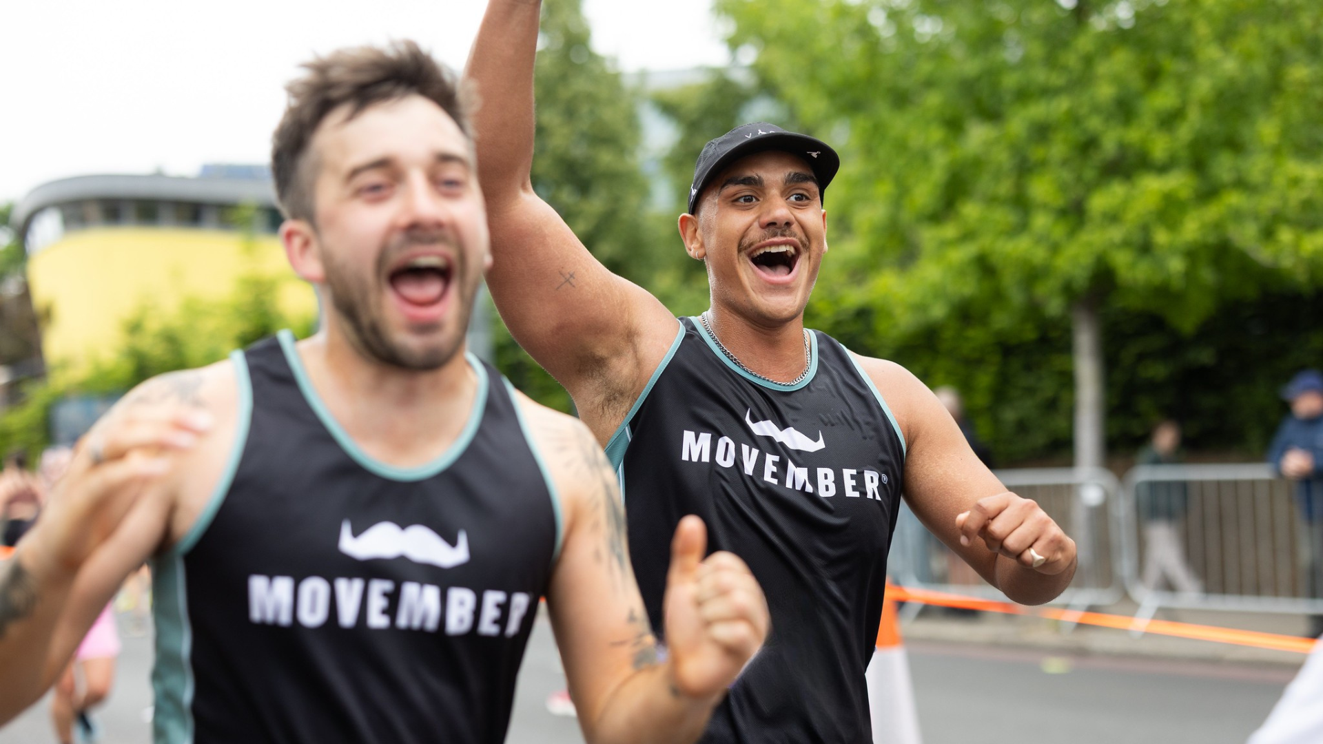 Two excited runners wearing Movember race tops passing by the camera