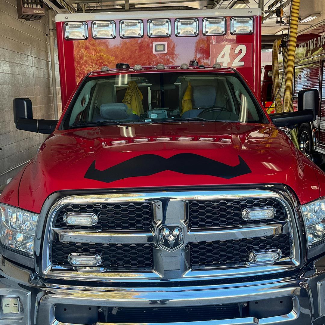 A fire truck with a moustache decal on the bonnet.